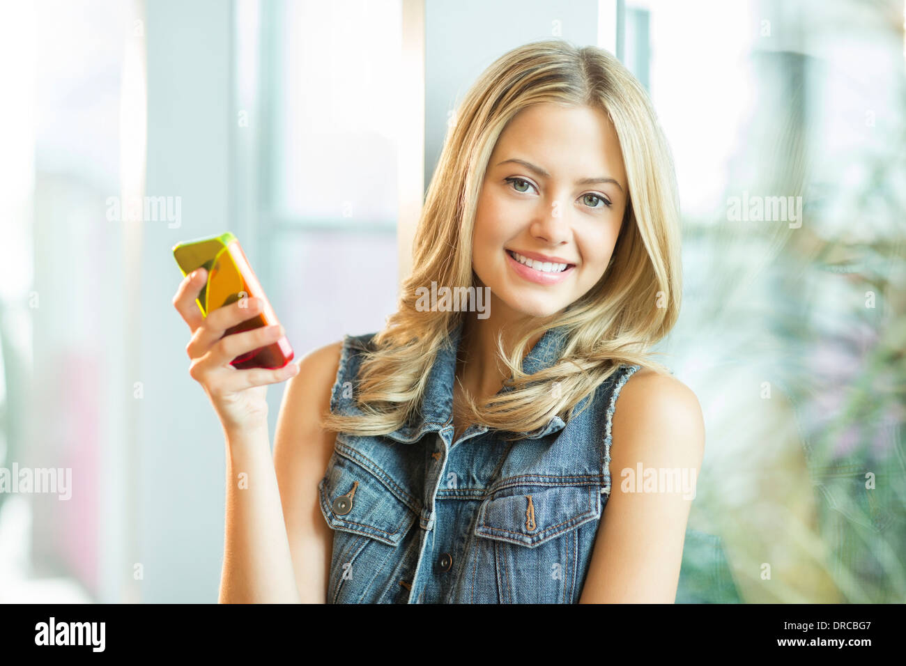 Frau mit Handy am Fenster Stockfoto