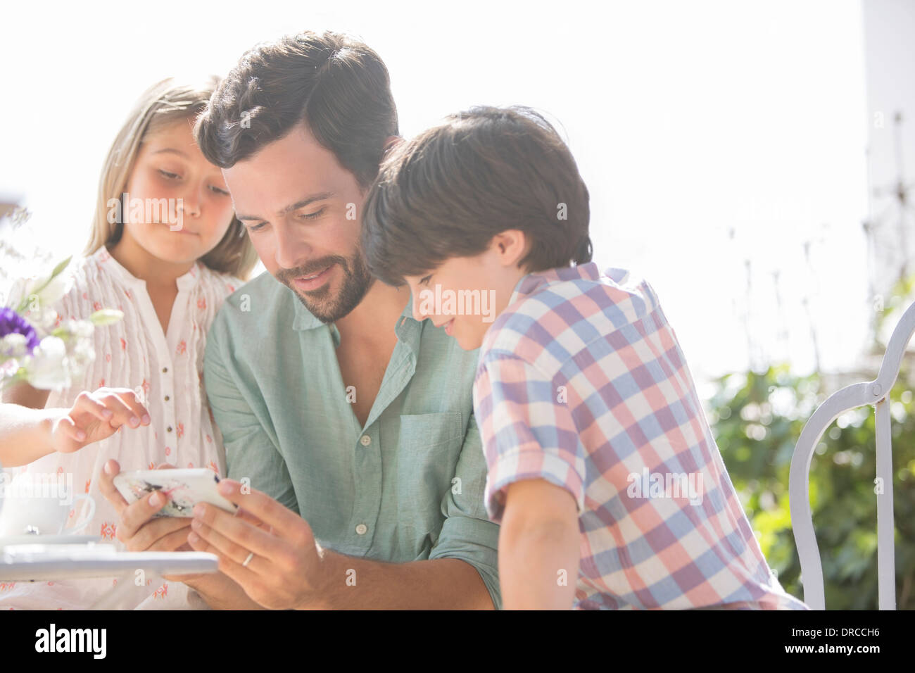 Vater und Kinder mit Handy im freien Stockfoto