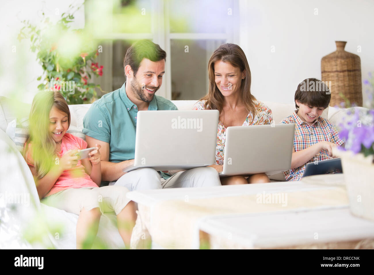 Familie mit Laptops, digitale Tablet und Handy auf Terrasse sofa Stockfoto