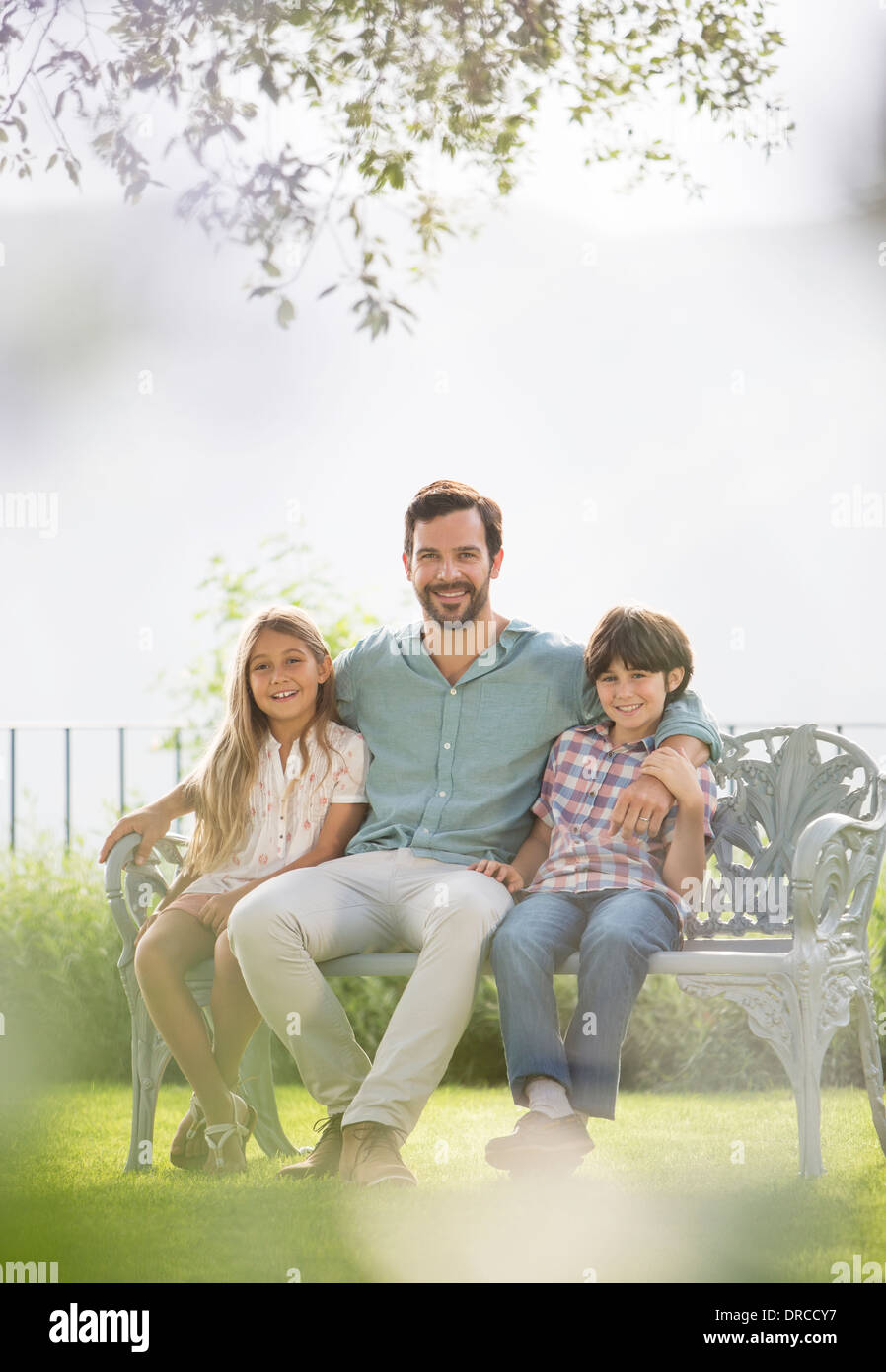 Vater und Kinder entspannend auf Parkbank Stockfoto