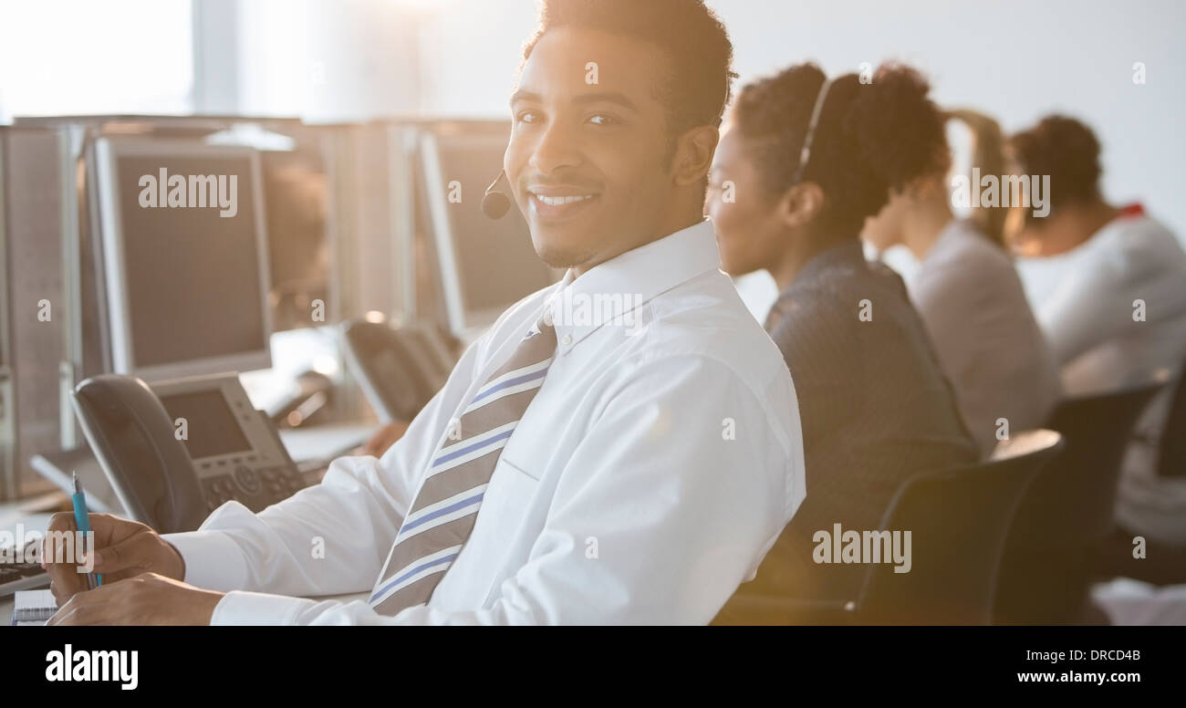 Geschäftsmann mit Kopfhörer lächelnd in Büro Stockfoto