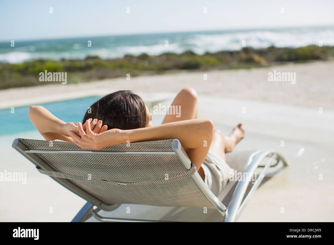 Frau im Liegestuhl am Pool Sonnenbaden Stockfoto