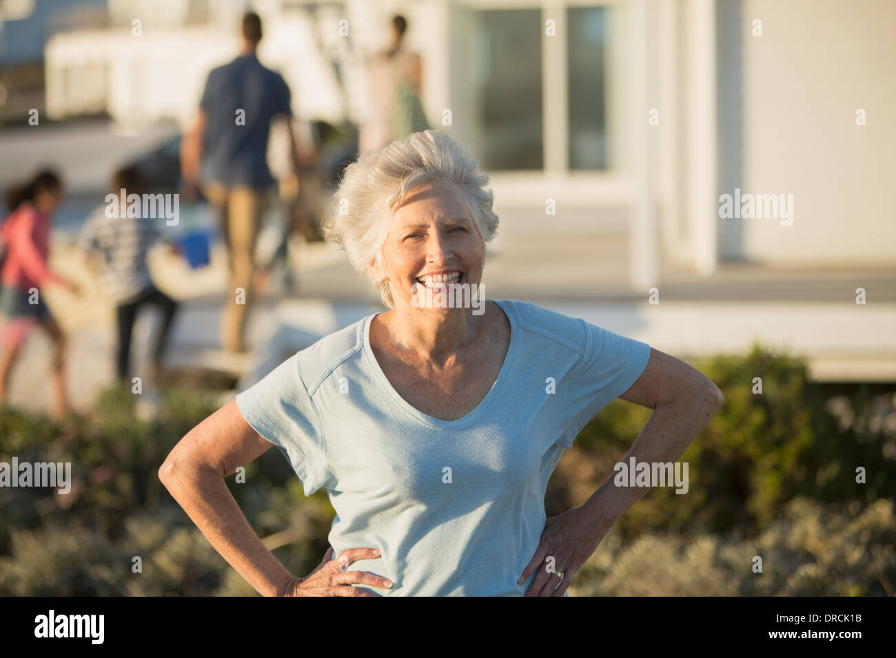 Ältere Frau lächelnd mit Hände auf den Hüften im freien Stockfoto