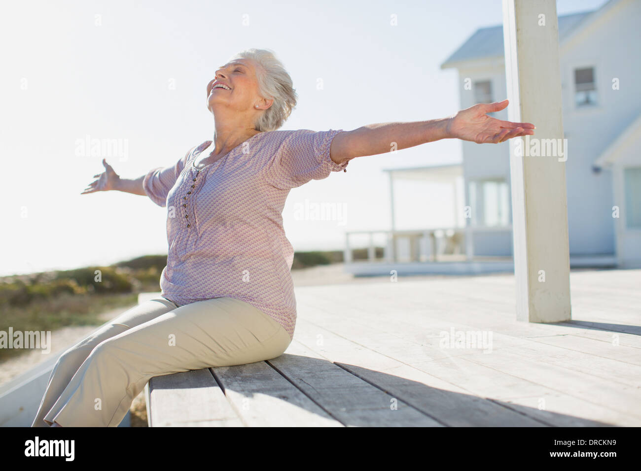 Ältere Frau mit ausgestreckten auf sonnigen deck Stockfoto