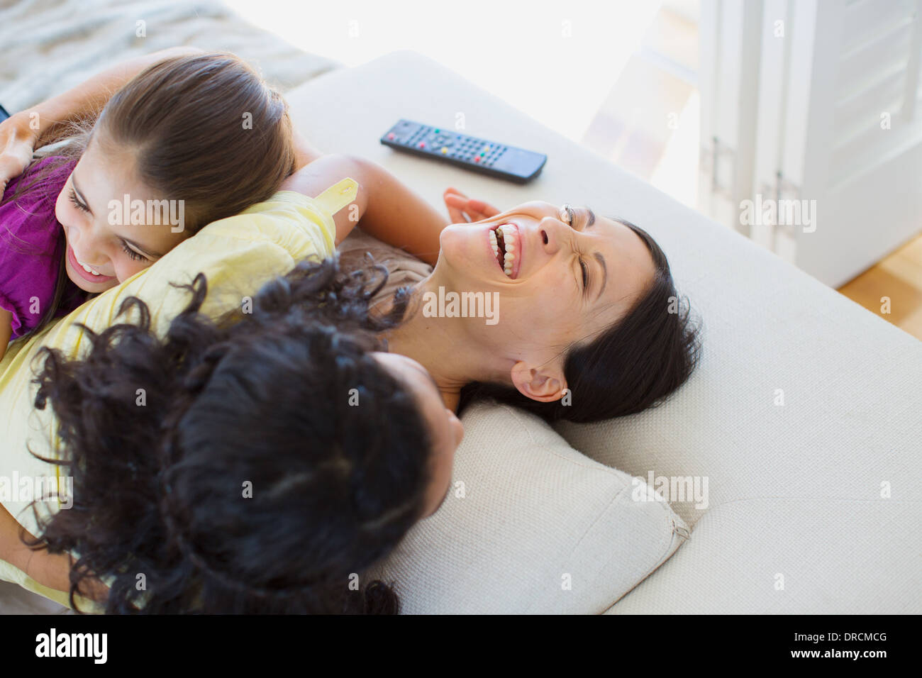 Mutter und Töchter Lachen auf sofa Stockfoto