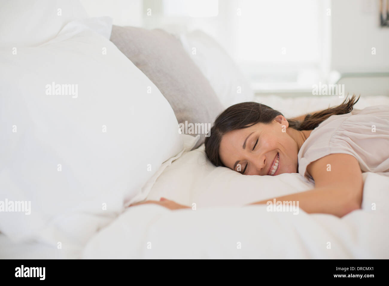 Lächelnde Frau auf Bett Stockfoto