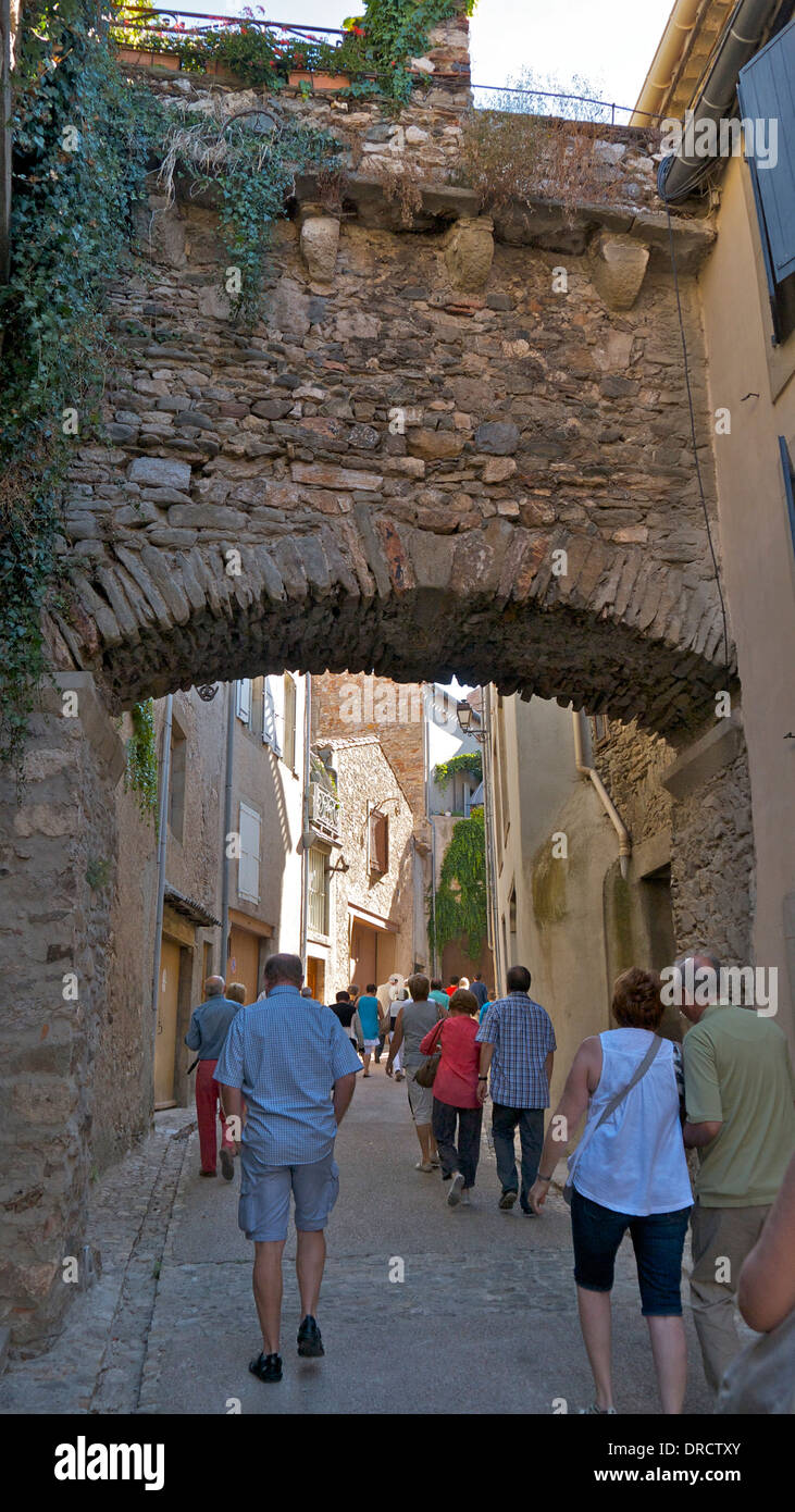 Eine alte Brücke über eine gepflasterte Straße in der historischen Altstadt Caunes-Minervios, Südfrankreich. Stockfoto