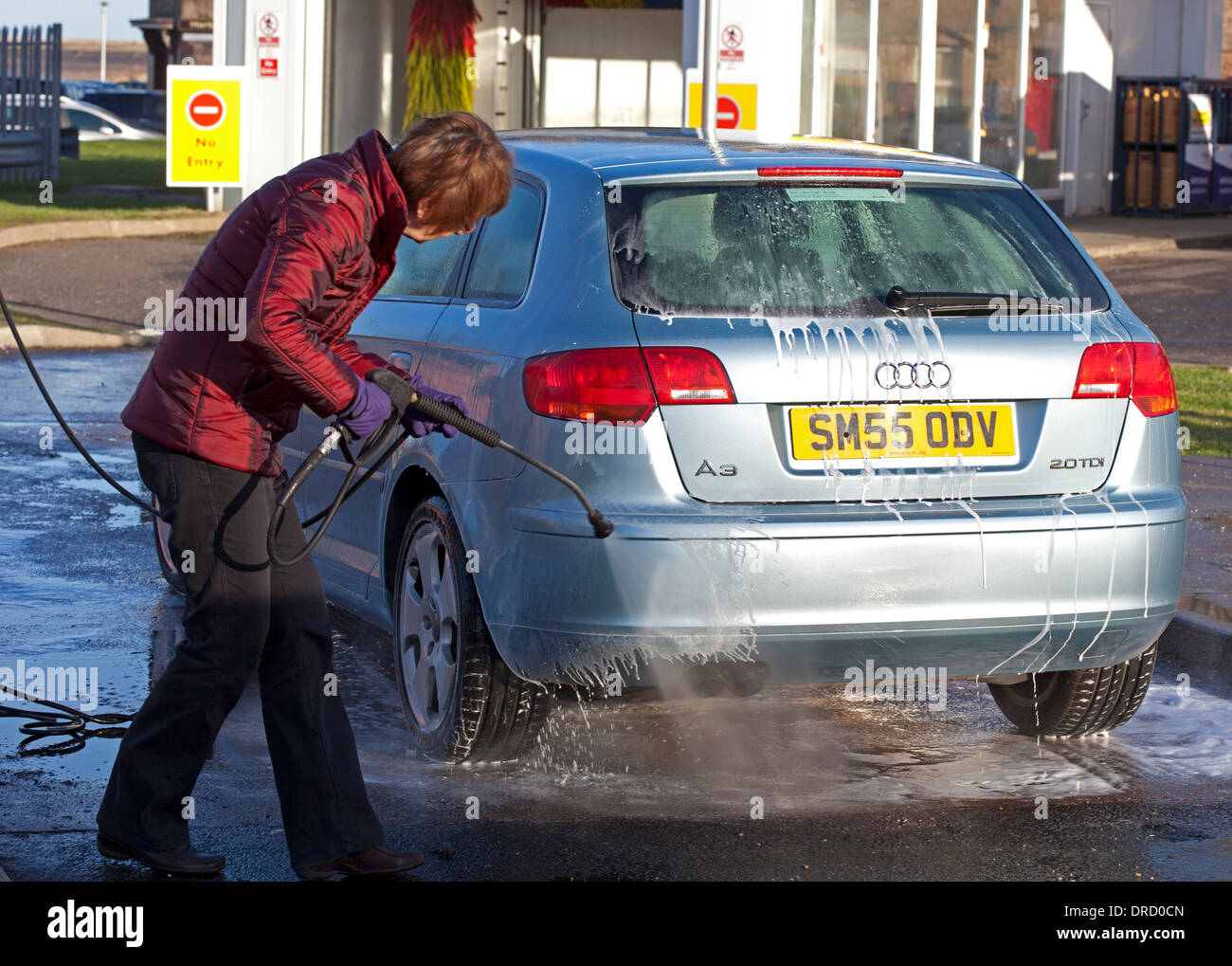 Frau Waschen Auto mit Jet Wash spray Stockfoto