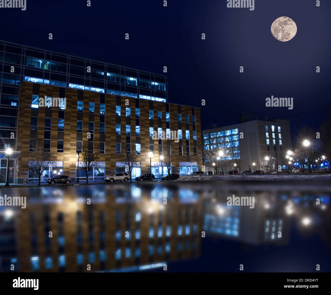 Bürogebäude am Franklin street in der Innenstadt von Syracuse, New York, im Winter nachts spiegelt sich in nassen Parkplatz Stockfoto