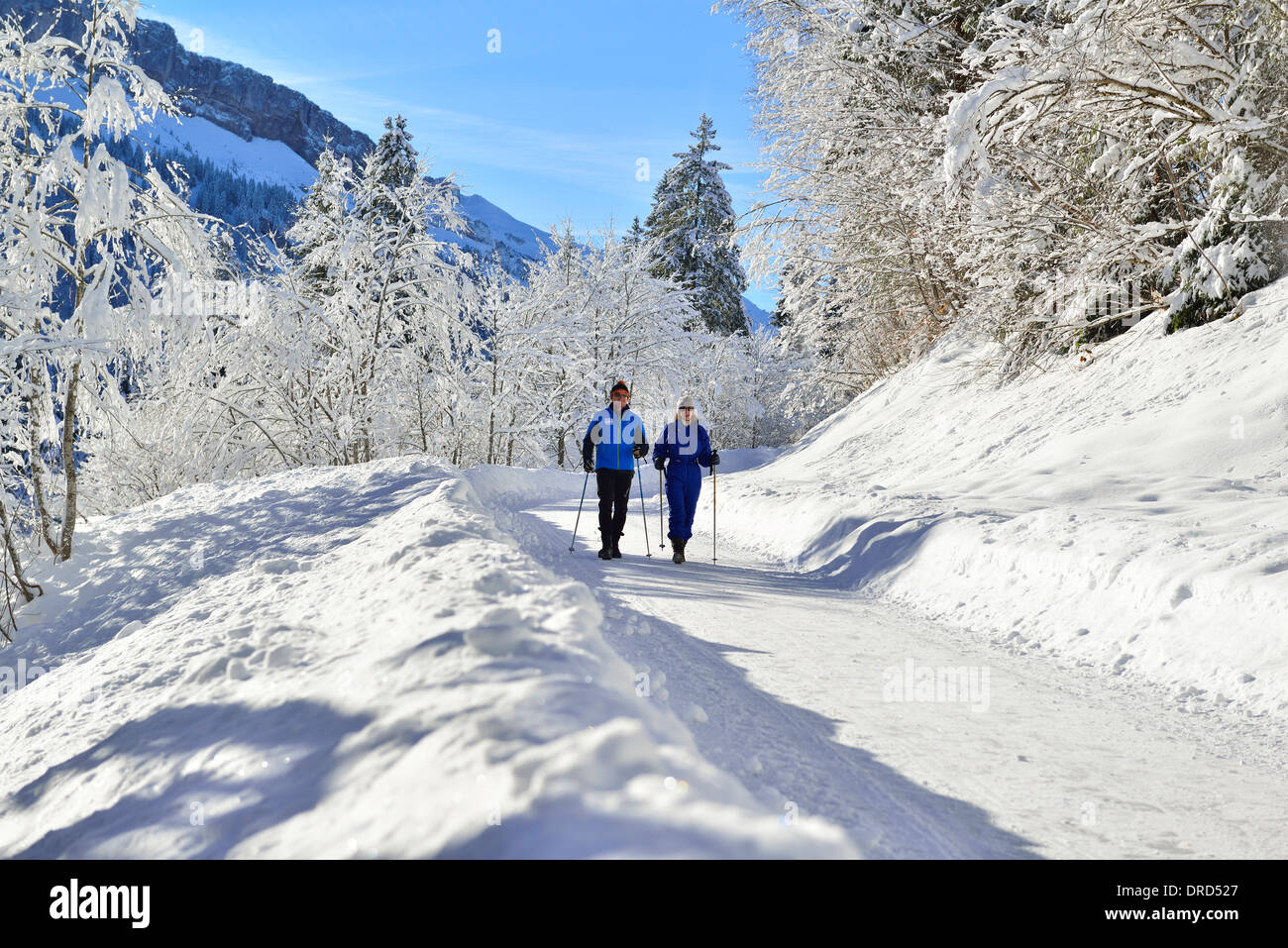 Mann und Frau wandern mit Stöcken im Winterwunderland des Rohrmoos-Tals (Tiefenbach) etwas außerhalb von Oberstdorf im Allgäu, Bayern, Deutschland Stockfoto