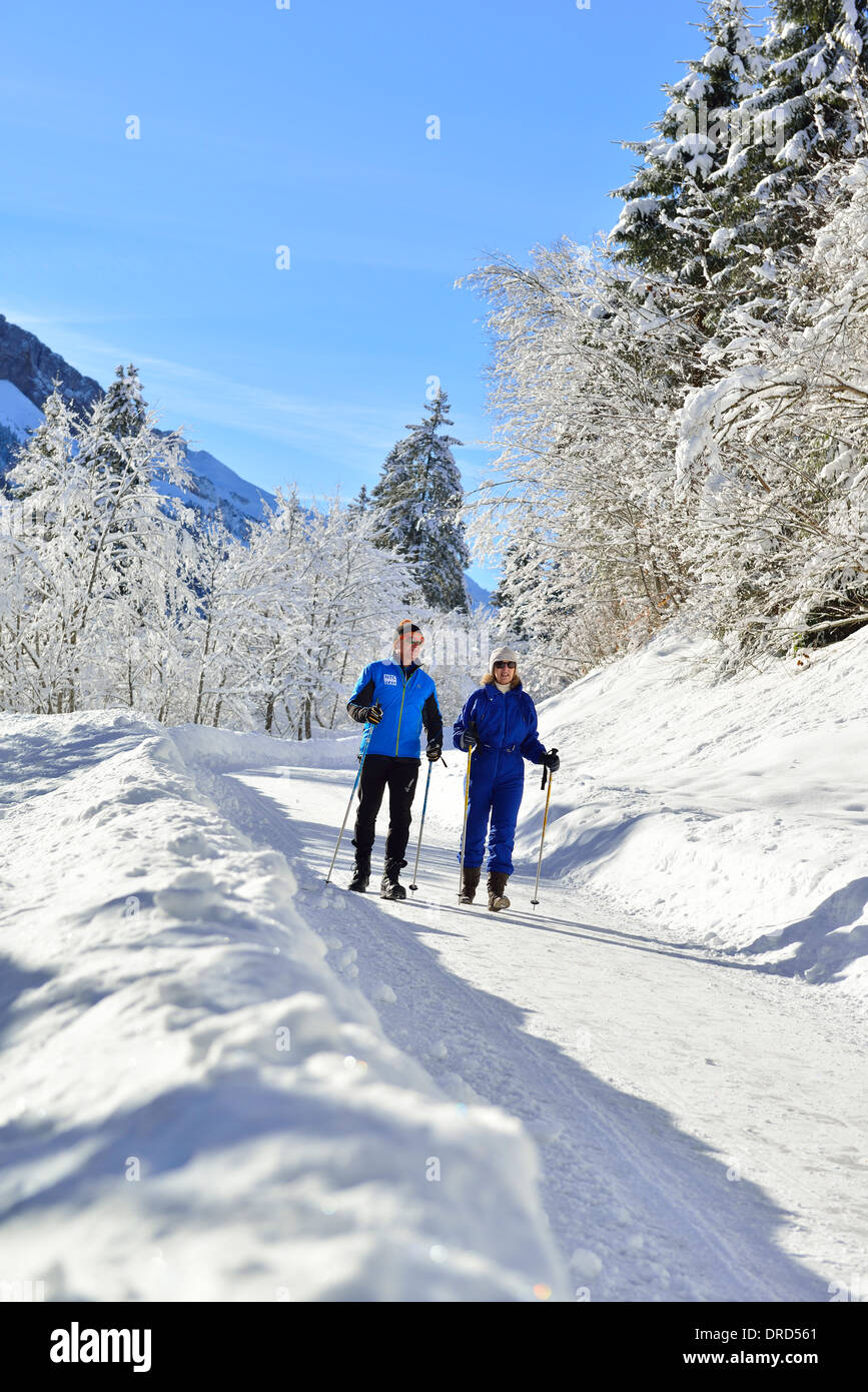 Mann und Frau wandern mit Stöcken im Winterwunderland des Rohrmoos-Tals (Tiefenbach) etwas außerhalb von Oberstdorf im Allgäu, Bayern, Deutschland Stockfoto