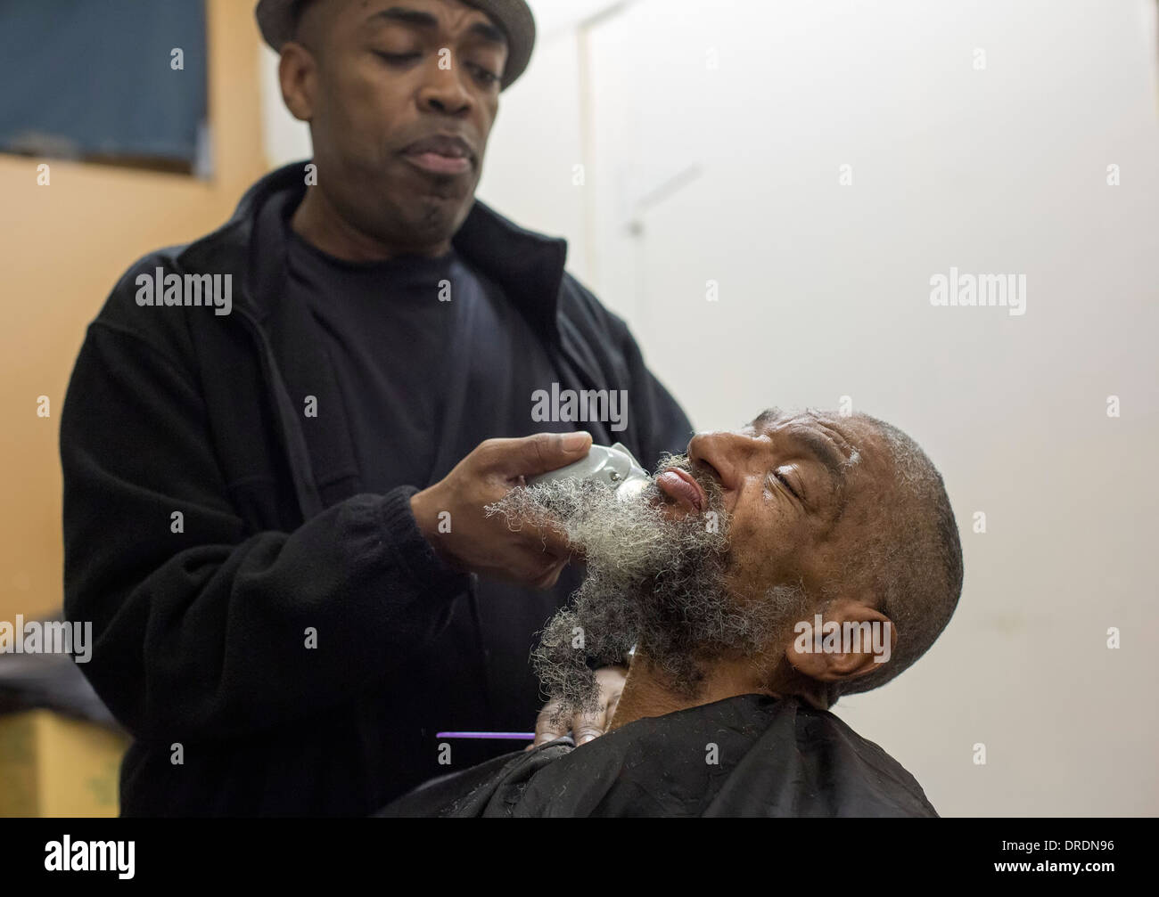 Detroit, Michigan - Barber Elvis Tucker gibt einen Haarschnitt und Rasur, ein Obdachloser Stockfoto