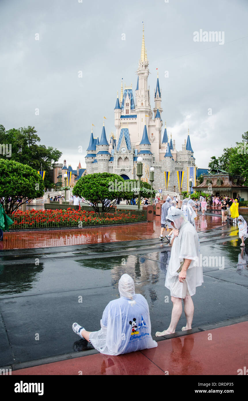 Familien in Ponchos im Regen im Walt DIsney World, Orlando, Florida mit dem Magic Kingdom Schloss im Hintergrund. Stockfoto