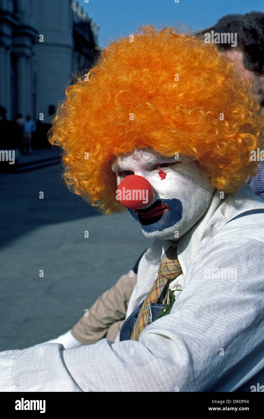 Eine Straße Mime tragen orange Lockenperücke nimmt sich eine Auszeit von seinen stillen Bürgersteig Performances für Touristen in New Orleans, Louisiana, USA. Stockfoto