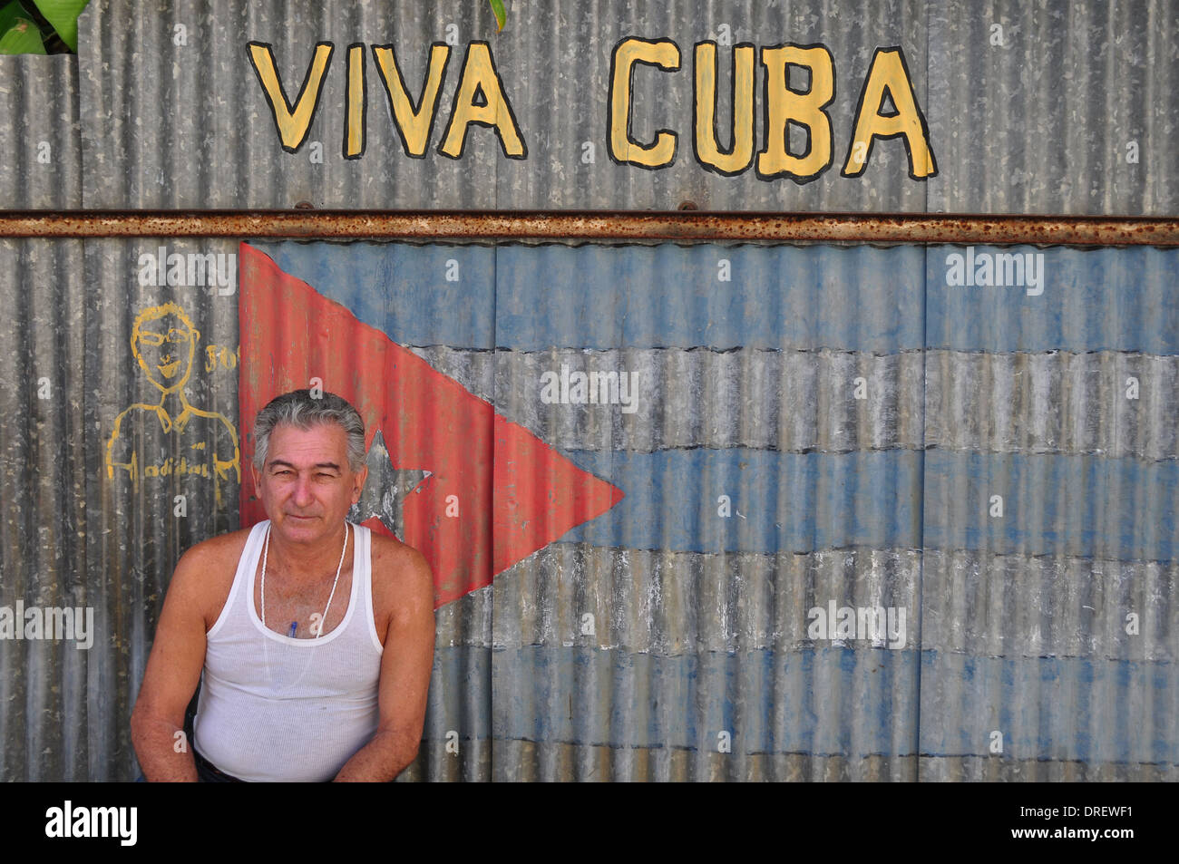 Havanna, Kuba: Mann sitzt neben Schild mit der Aufschrift Viva Cuba im Casa Blanca Bezirk der Stadt. Stockfoto