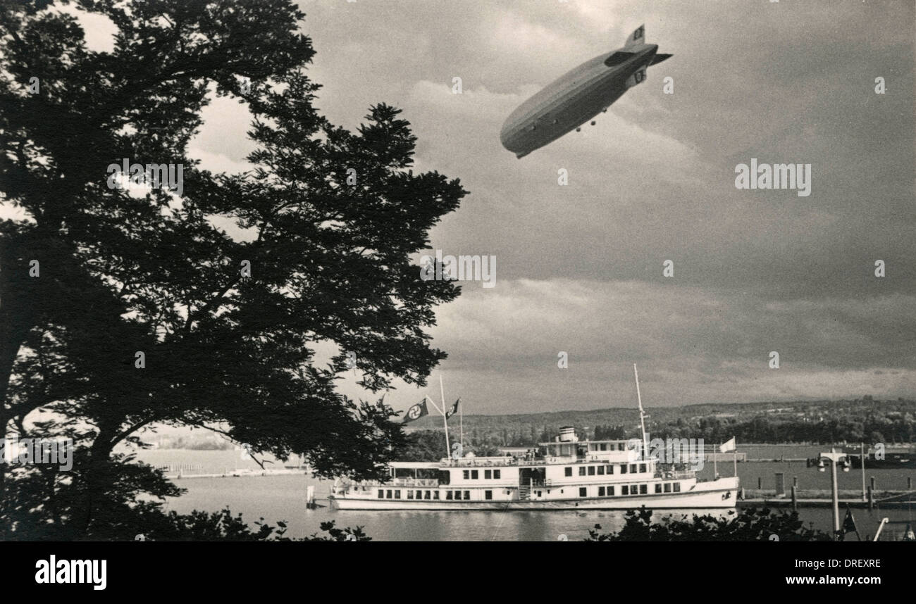 Hakenkreuze fliegen auf einem Boot, wie ein Zeppelin über dem Kopf fliegt. Stockfoto