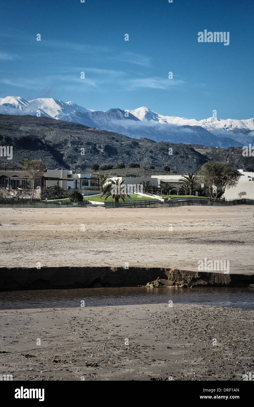 Winter auf der Insel Kreta mit einem Sandstrand, Hotel/Villen, Ausläufer, schneebedeckte Berge und blauer Himmel. Stockfoto