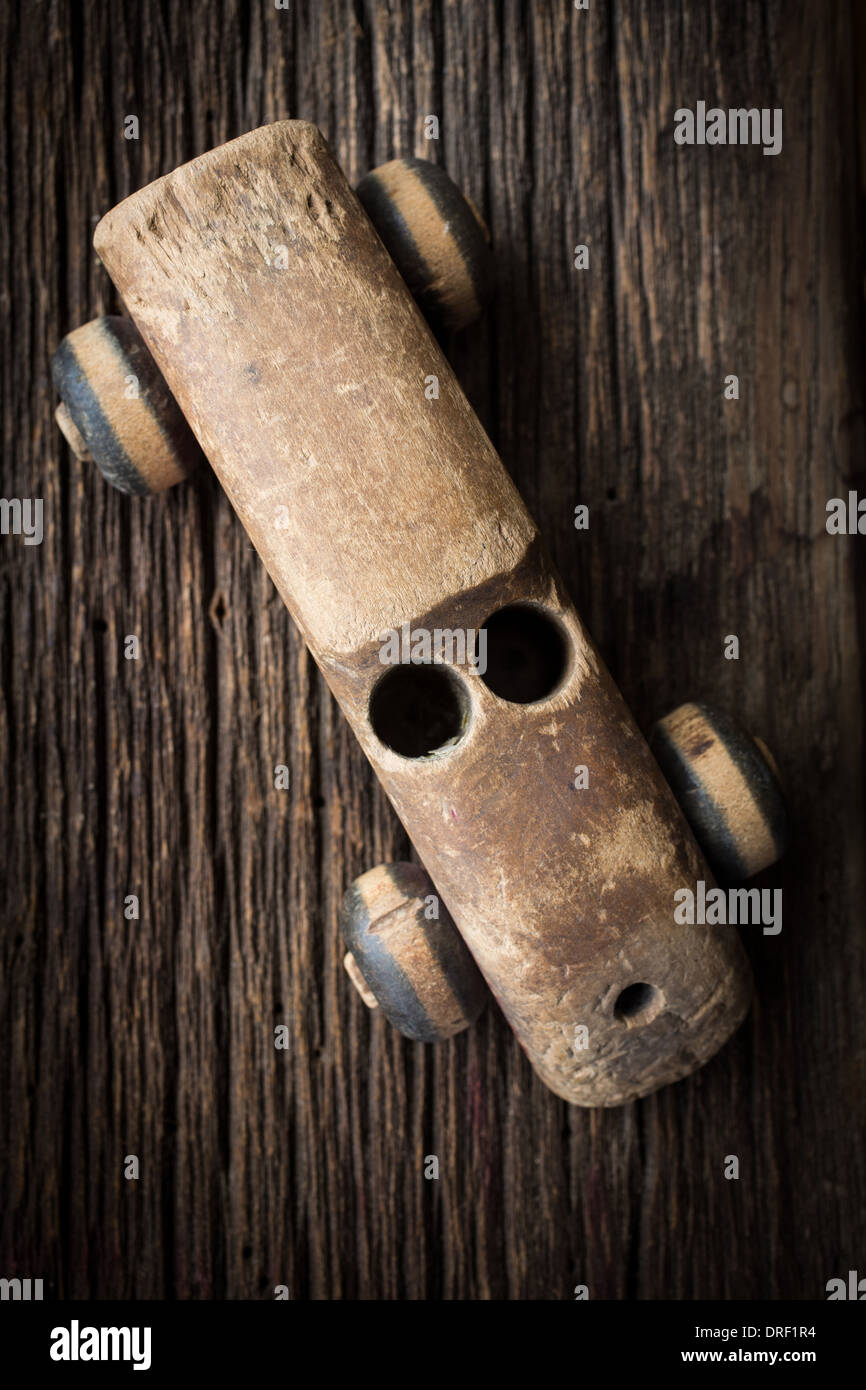 Ein altes hölzernes Spielzeugauto verwittert aus jahrelanger spielen auf einem rustikalen alten Boden. Stockfoto