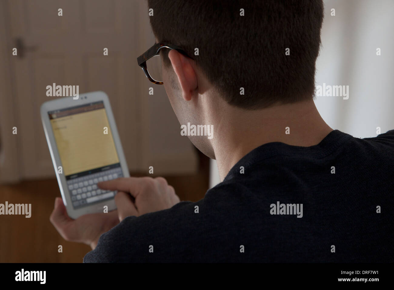 Über Schulter Schuss von Mann mit Brille, die Eingabe über eine Tastatur auf dem Touch-Bildschirm digitale Tablett. Stockfoto