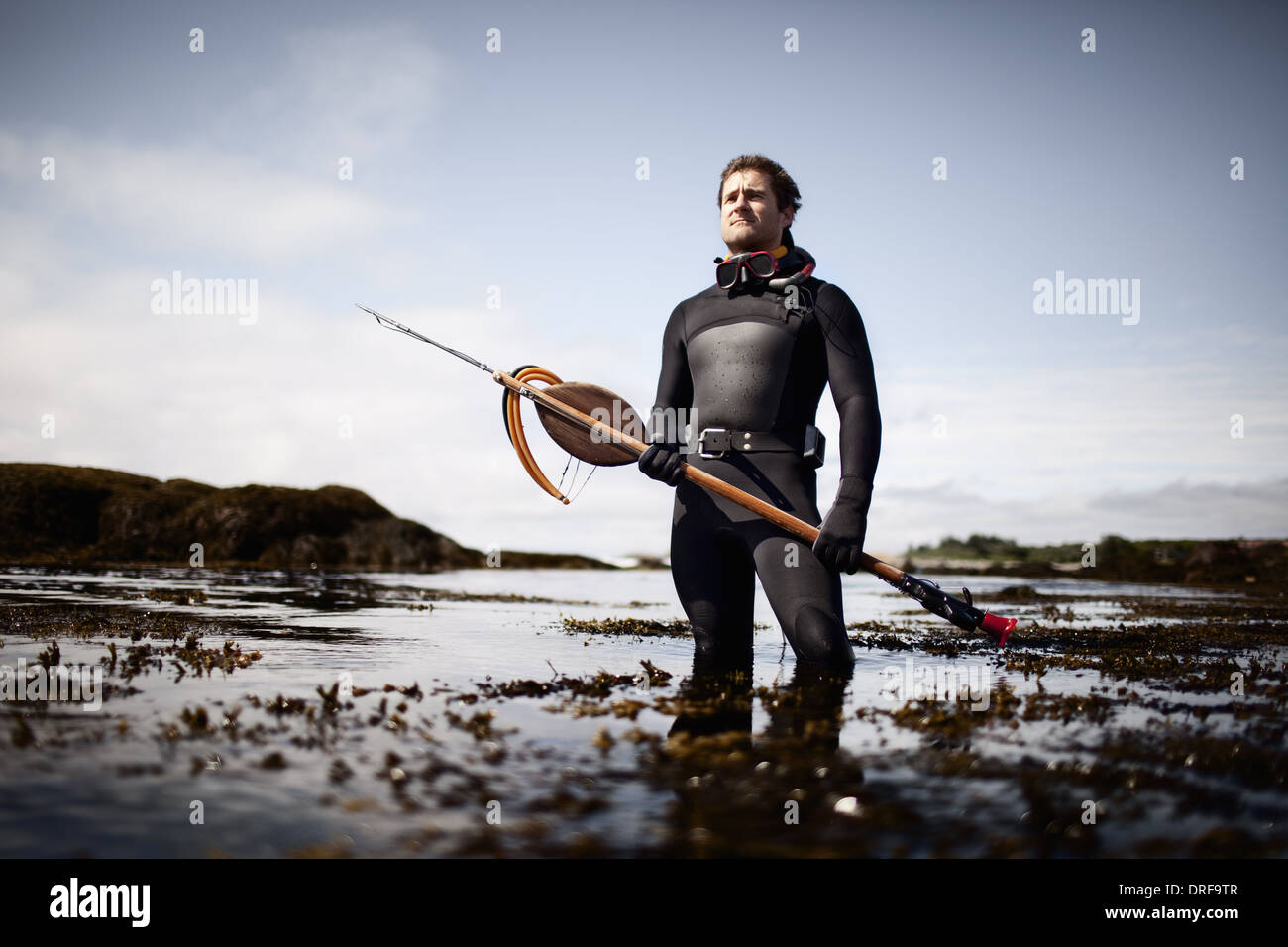 USA-Mann im Neoprenanzug stehende Ufer große Speer Harpune Stockfoto