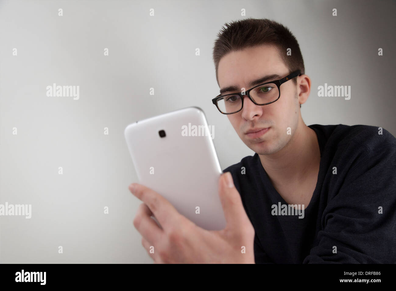 Gut aussehender junger Mann mit Brille, hält eine weiße digitale-Tablette. Form, mit textfreiraum Landschaft. junger Mann mit digita Stockfoto