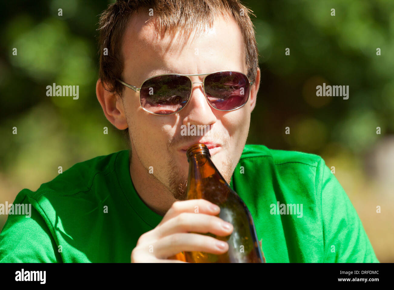 Nahaufnahme eines Jünglings glücklich trinken Bier aus der Flasche im Freien. Stockfoto