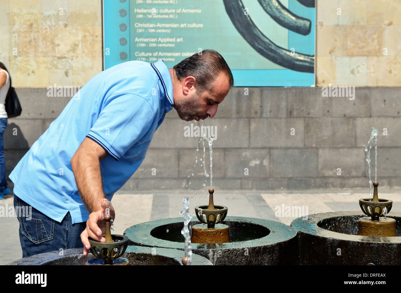 Ein Mann erfrischt sich mit natürlichen Trinkwasser aus einer Quelle in Eriwan Stockfoto