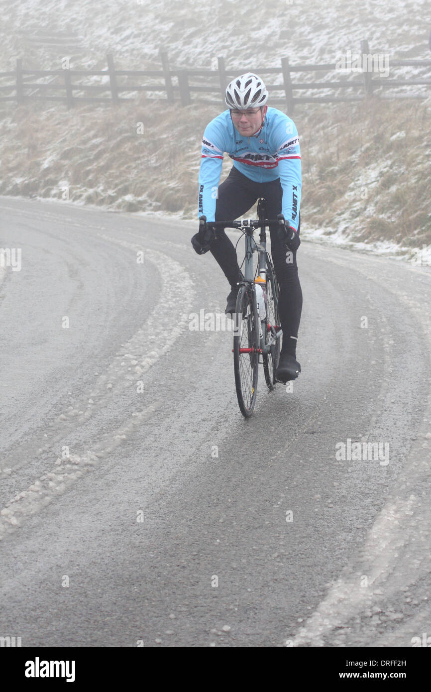 Ein Radfahrer befasst sich Nebel und verschneiten Straßenverhältnisse angrenzend an Mam Tor in Castleton, Peak District National Park, England, UK Stockfoto