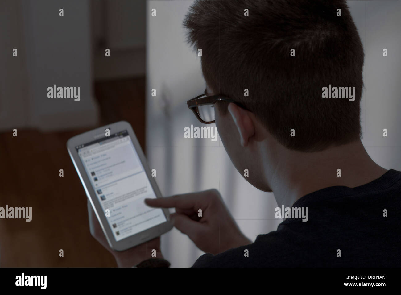Junger Mann mit Brille sitzen mit einem Mini-digital-Tablette.  Ansicht von hinten über die Schulter geschossen. Networking-Website. Stockfoto