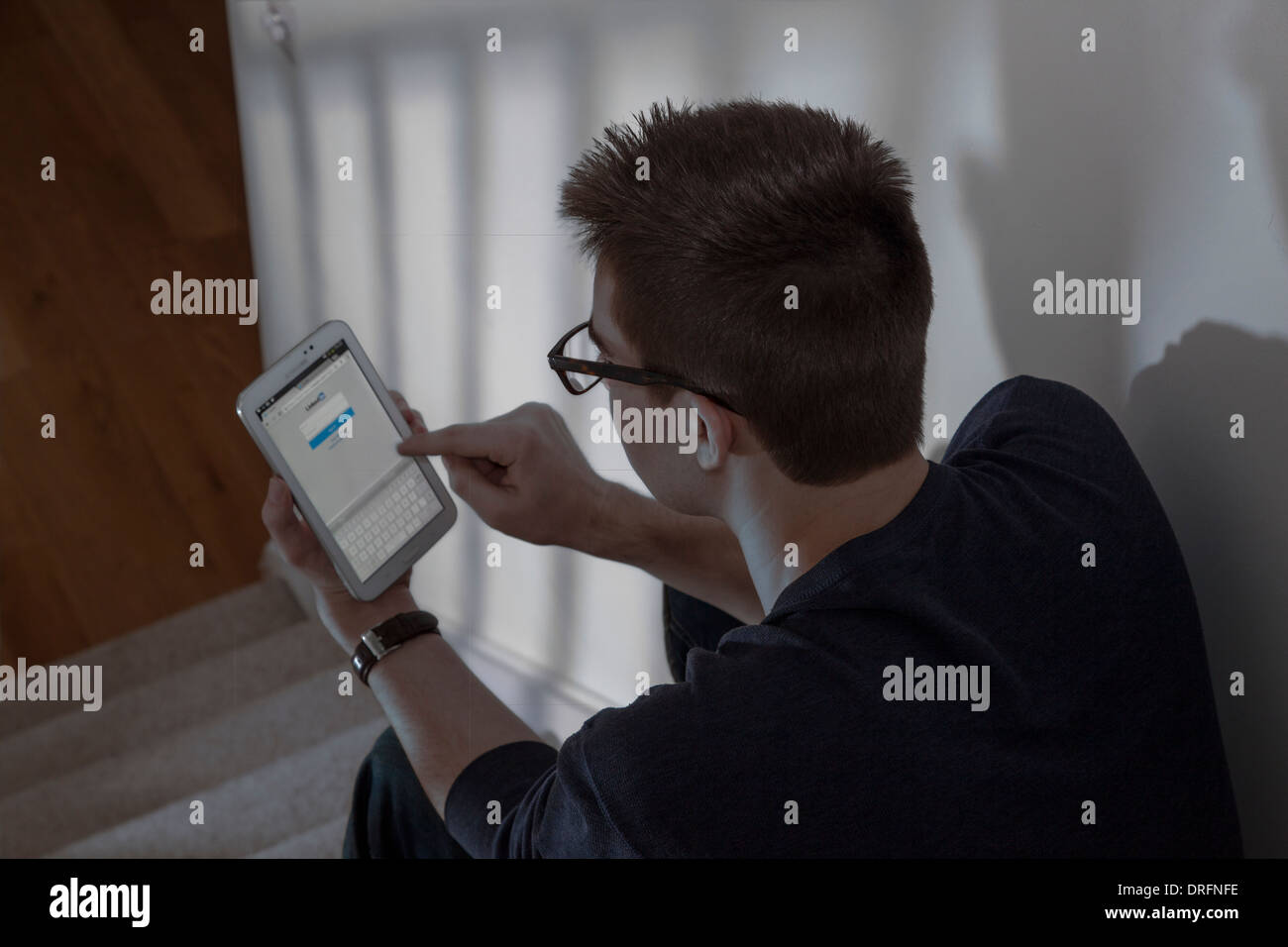 Junger Mann mit Brille sitzen mit einem Mini-digital-Tablette.  Ansicht von hinten über die Schulter geschossen. Networking-Website. Stockfoto