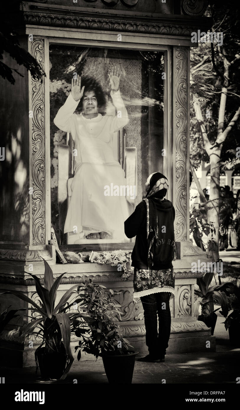 Indische Frau beten zu einem Bild von Sathya Sai Baba auf Super-Spezialklinik. Puttaparthi, Andhra Pradesh, Indien. Sepia Stockfoto