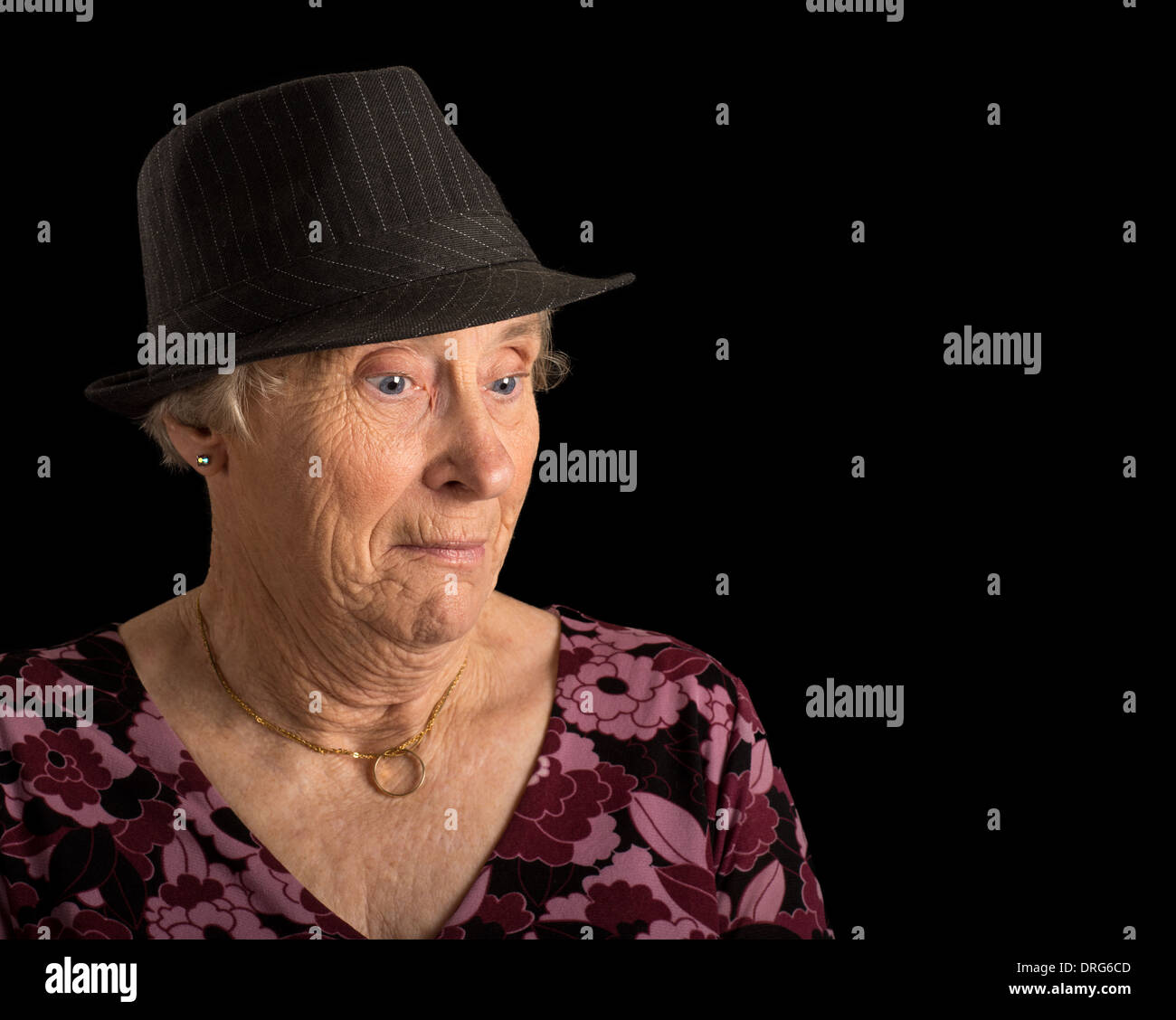 Ältere Dame mit einem schockiert Blick auf ihrem Gesicht trägt eine Fedora isoliert auf schwarz Stockfoto