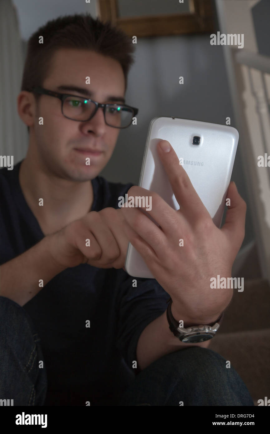 Junger Mann mit Brille sitzen mit einem Mini-digital-Tablette. Stockfoto