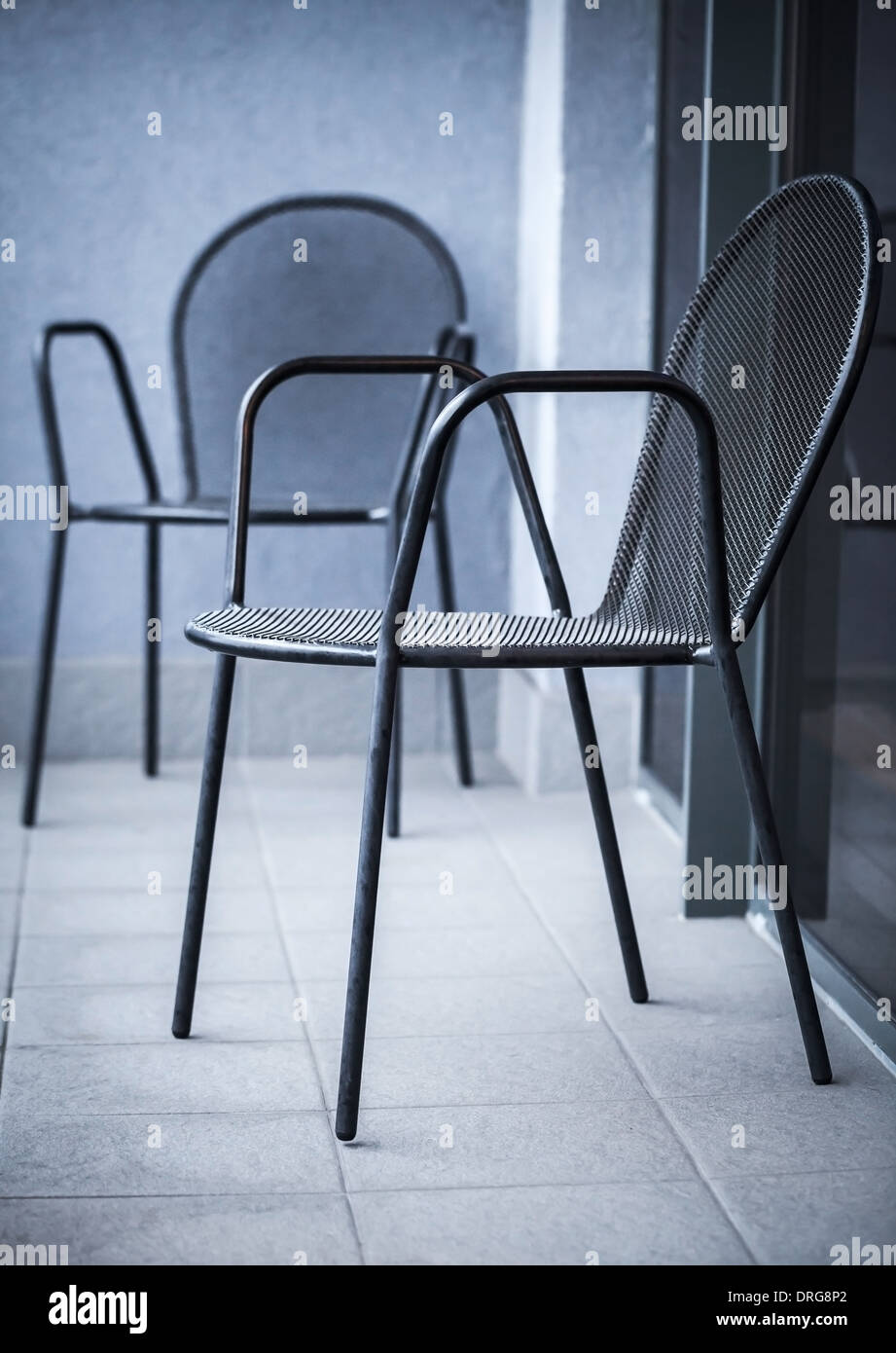 Gewöhnliche schwarze Metall-Stühle stehen auf dem Balkon Stockfoto
