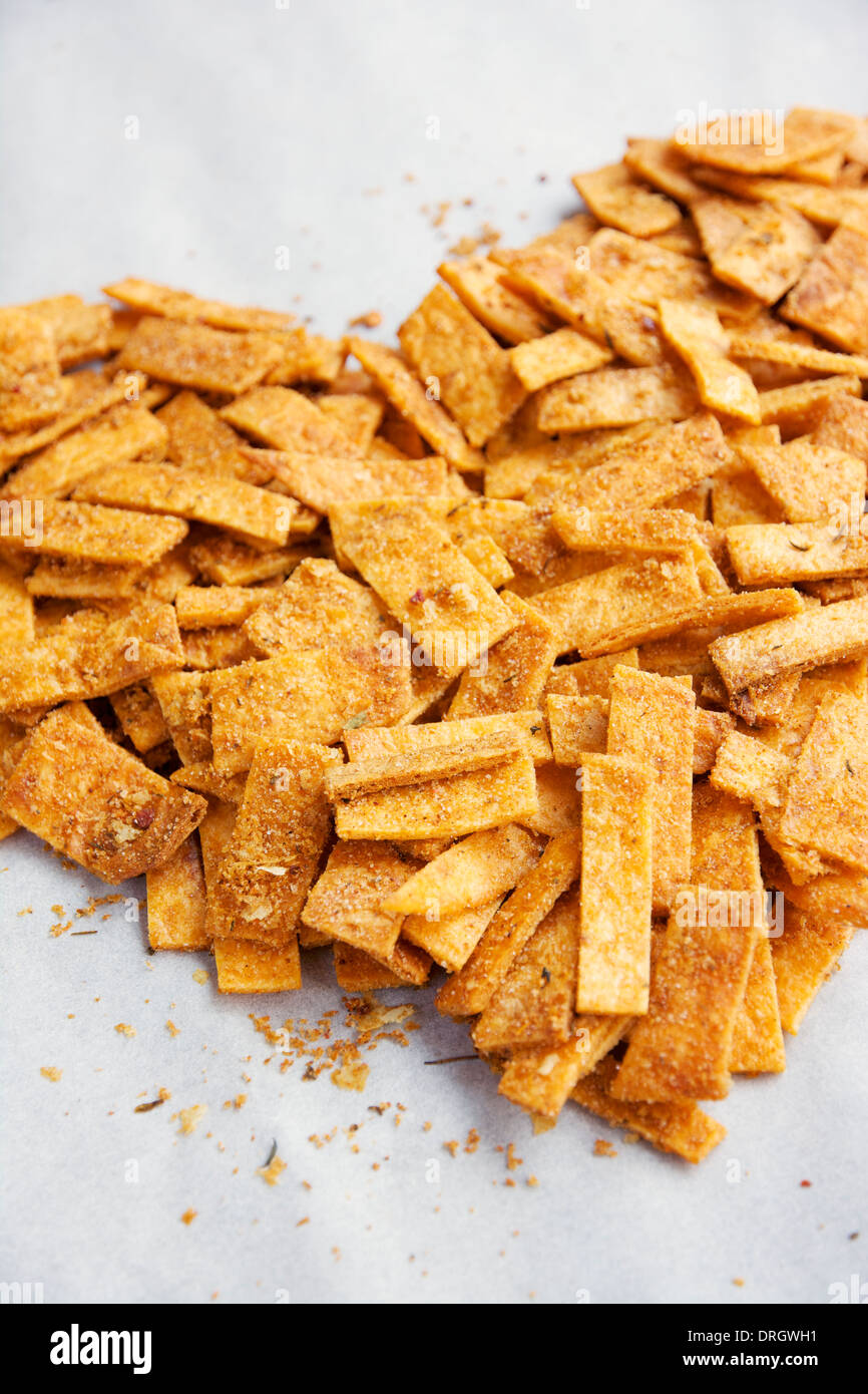 Streifen von hausgemachte pikante Mehl Tortillachips, angeordnet in Form eines Herzens auf Pergamentpapier. Stockfoto