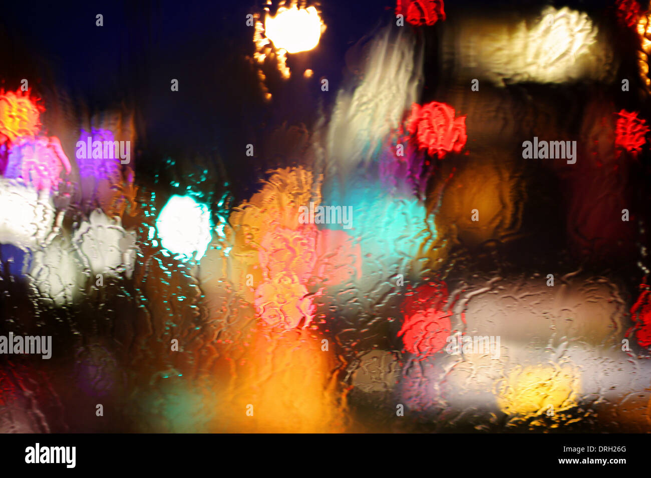 Lichter in der Nacht durch Regentropfen auf Glas genommen Stockfoto