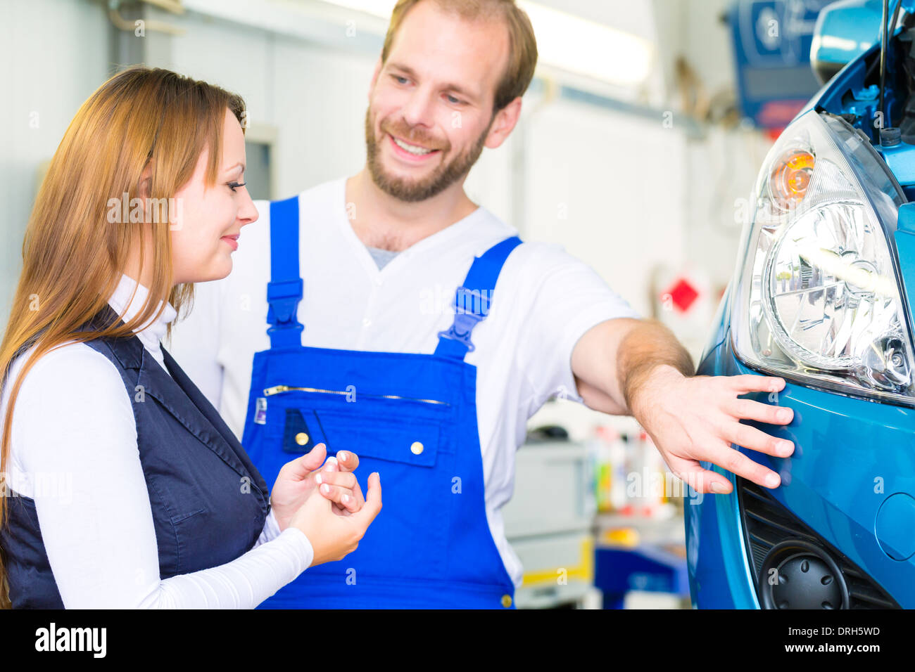 Kundin und Mechaniker in der Werkstatt oder MOT mit Auto für Service-Inspektion Stockfoto