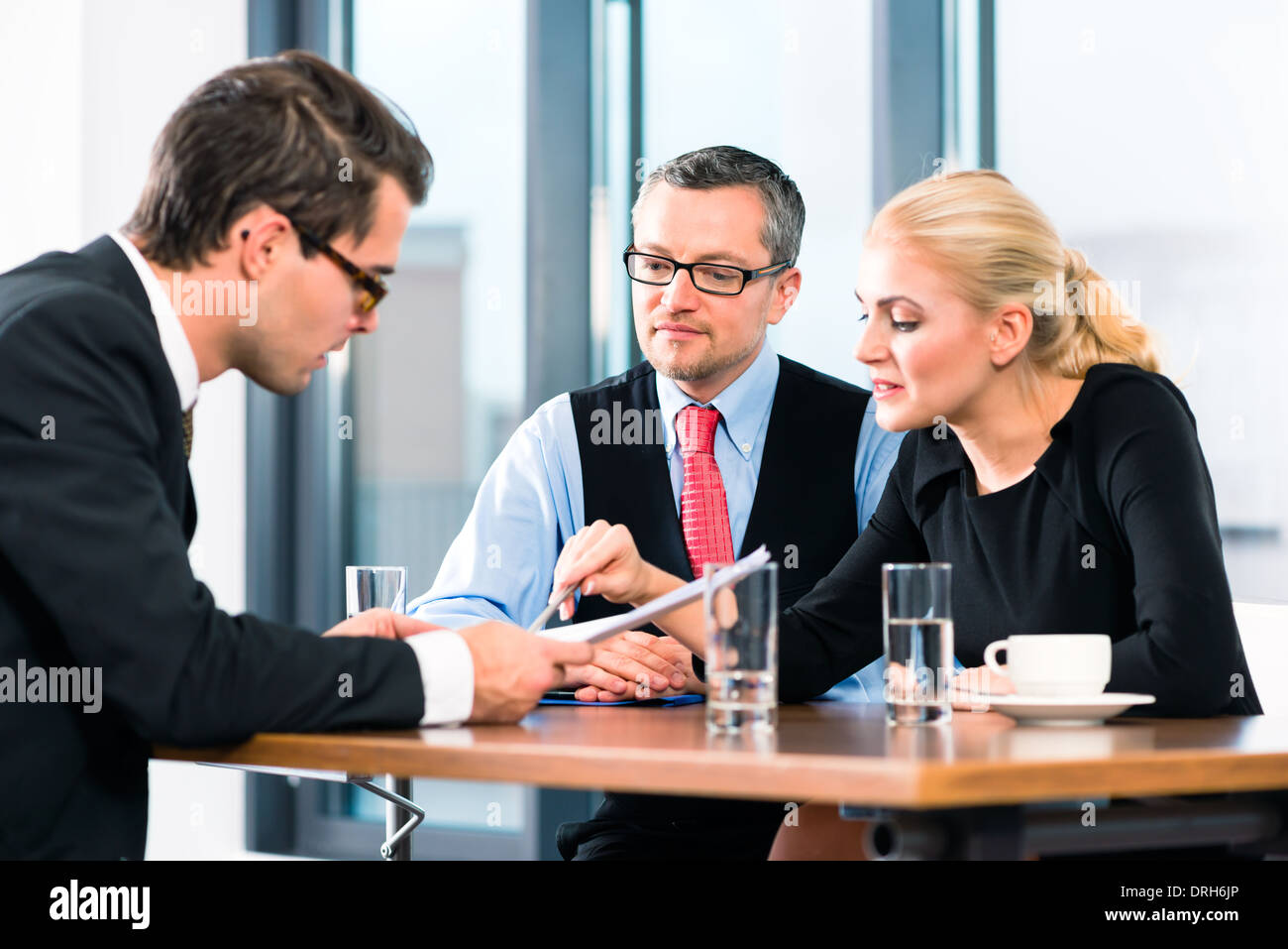 Business - junger Mann in einem Job-Interview, Zeichen seines Arbeitsvertrags mit Chef und seine Assistentin in ihrem Büro Stockfoto