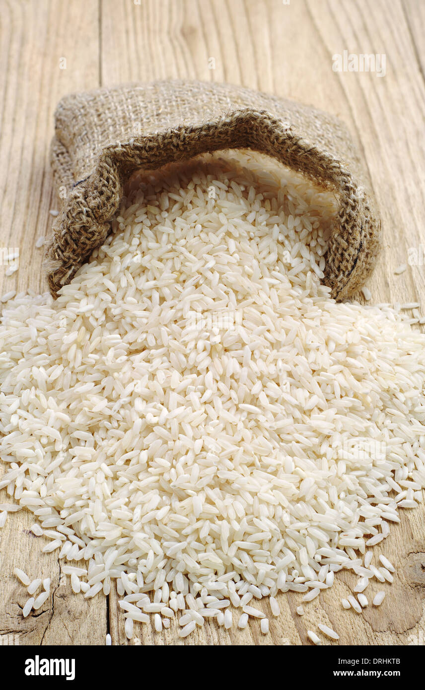 Reis in Holztisch und kleiner Leinensack Stockfoto