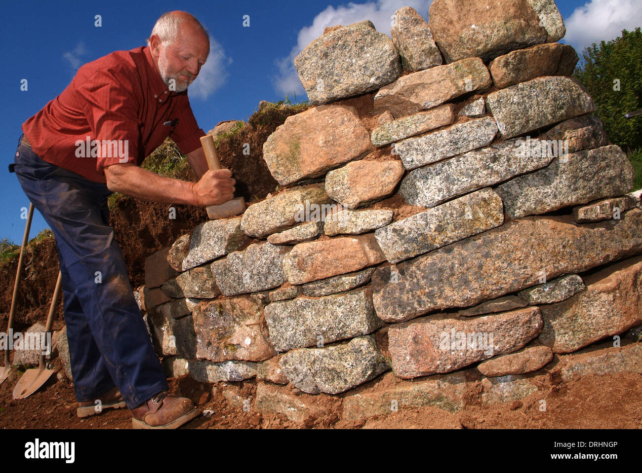 Trockenmauer Builder, David hannaforth mit nichts als Granit Stein, den er spaltet sich von großen Felsbrocken. Stockfoto