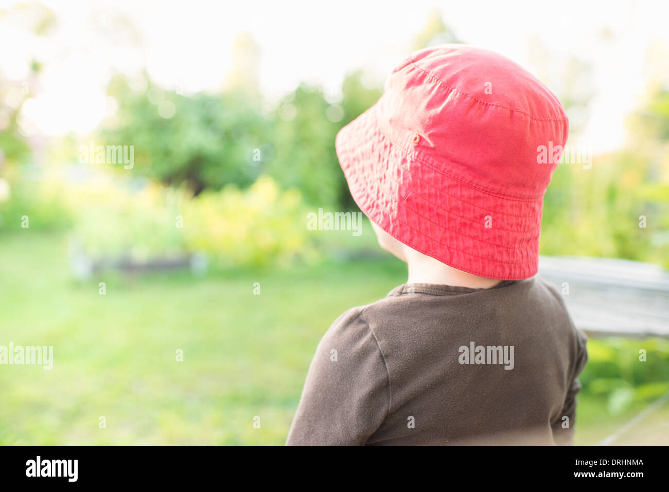 Ruhigen Sommer-Szene. Junges Mädchen sitzt im Garten, Pflanzen und Blumen zu beobachten. Stockfoto