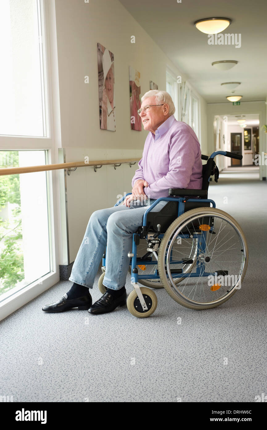 Ältere Mann sitzt im Rollstuhl, Blick durch Fenster, Bayern, Deutschland Stockfoto