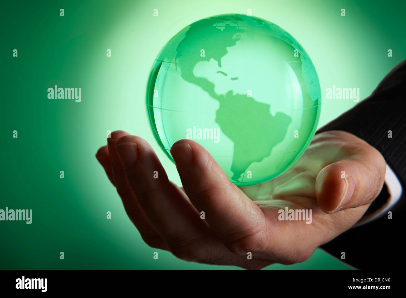Glas green globe glühende in Palm von businessmans Hand Stockfoto