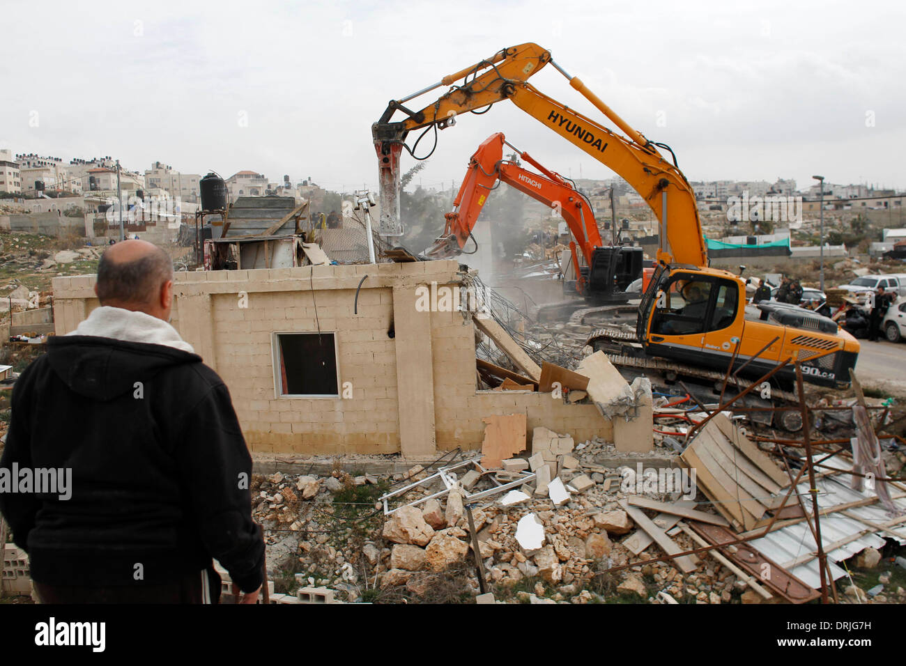 Jerusalem. 27. Januar 2014. Israelische Gemeinde Arbeiter benutzen mechanische Bagger, um ein Haus aus einer palästinensischen Familie, die die Behörden ohne städtische Berechtigung in der arabischen Osten Jerusalem Nachbarschaft von Beit Hanina, am 27. Januar 2014 glauben zu zerstören. Israelische Behörden befahl den Abriss der vier palästinensische Häuser gebaut, ohne erlaubt in den arabischen Vierteln von Issawija und Beit Hanina Gehäuse insgesamt 20 Mitarbeiter, Bewohner und Polizei Quellen zufolge. Bildnachweis: Muammar Awad/Xinhua/Alamy Live-Nachrichten Stockfoto