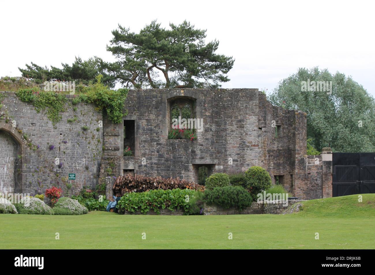 Burgmauer, Rundbogenfenster, Blumen im Fenster, Waldumgebung, Rasen Garten, gepflegter Rasen Stockfoto