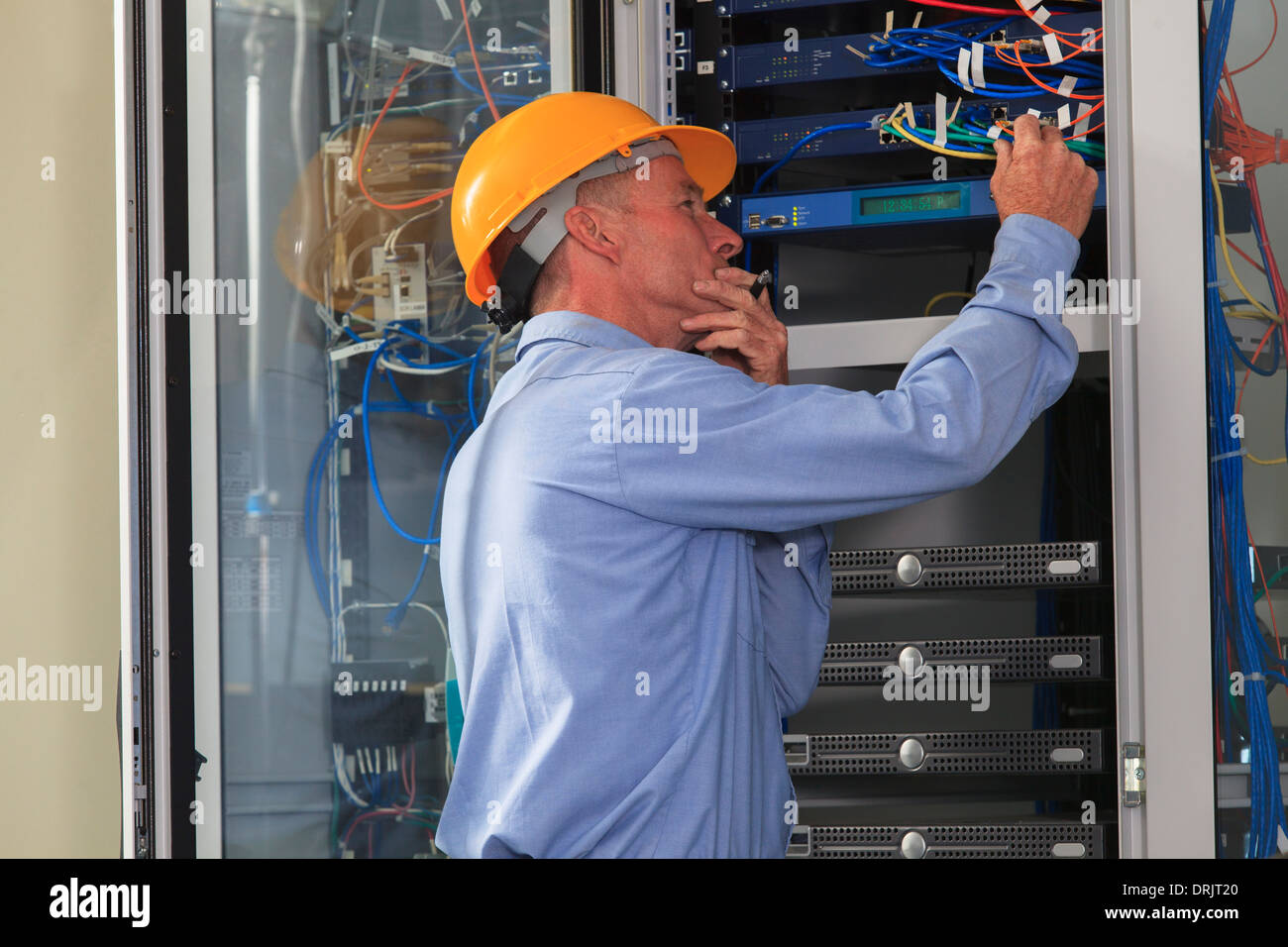 Elektro-Ingenieur arbeitet mit Switches und Server in Breitbandkommunikation Nabe des Kraftwerks Stockfoto