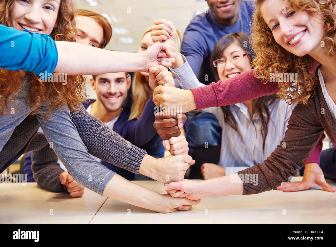 Studenten, die Fäuste für Kooperation und Teamarbeit in einer Universität stapeln Stockfoto