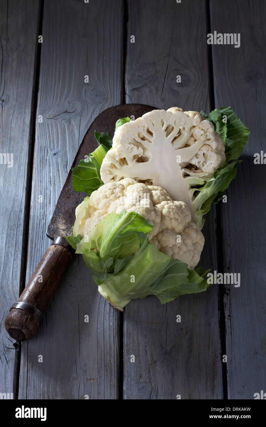 In Scheiben geschnittene Blumenkohl (Brassica Oleracea var. Botrytis L.) und antiken Wiegemesser auf grauem Holztisch Stockfoto