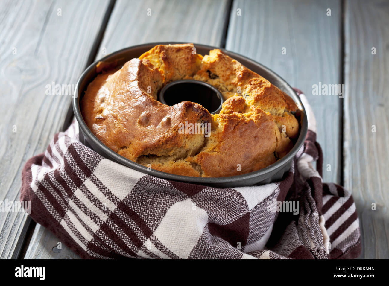 Kuchenform mit gebackenen Ring Kuchen und Küche Handtuch auf grauem Holztisch Stockfoto