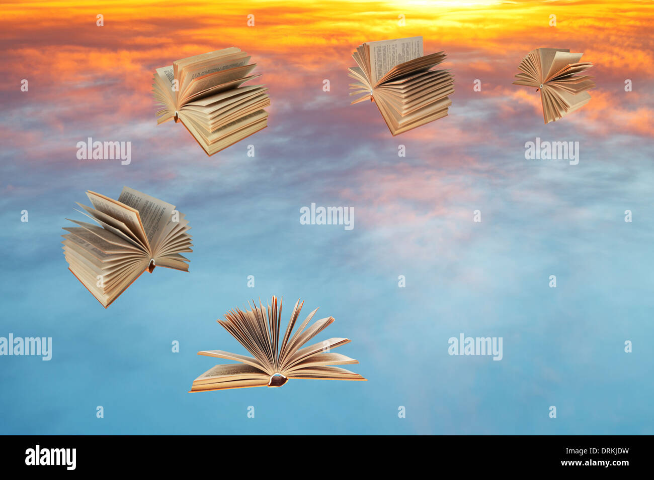 Bücher fliegen über blaue und gelbe Sonnenuntergang Wolken Stockfoto